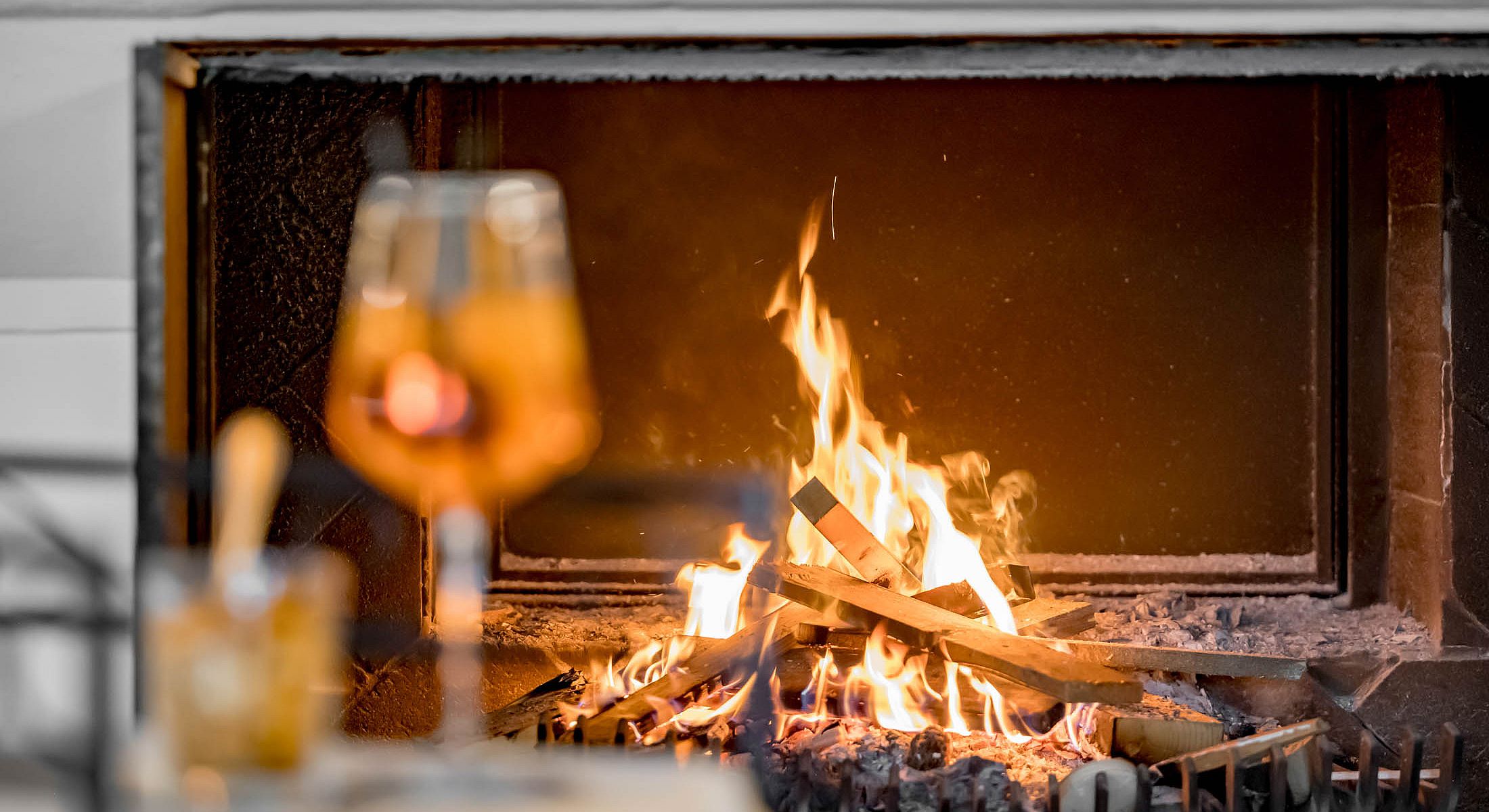 Offener Kamin mit loderndem Feuer und Getränk in gemütlicher Atmosphäre