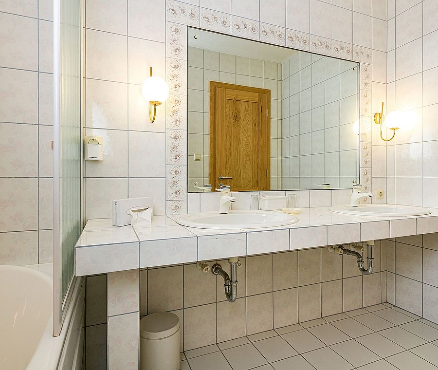Großes Badezimmer mit zwei Waschbecken, großer Spiegel, Badewanne und gefliesten Wänden