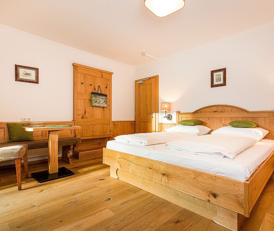 Helles Schlafzimmer mit Holzmöbeln, Doppelbett, Sitzecke und gemütlicher, alpiner Einrichtung