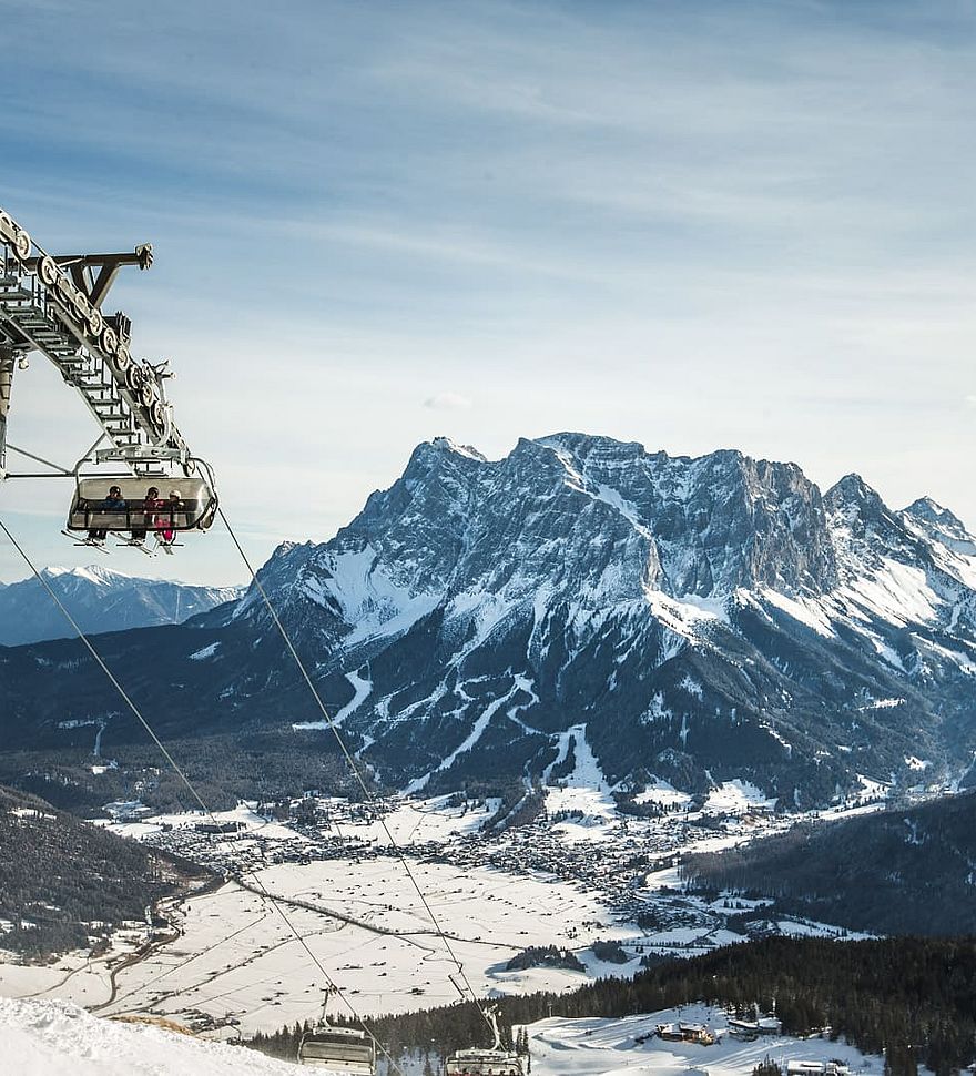 Stoeltjeslift met uitzicht op besneeuwde Zugspitze en het dal van Lermoos in de winter