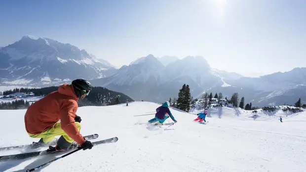 Group of skiers descending a sunny slope with mountain view