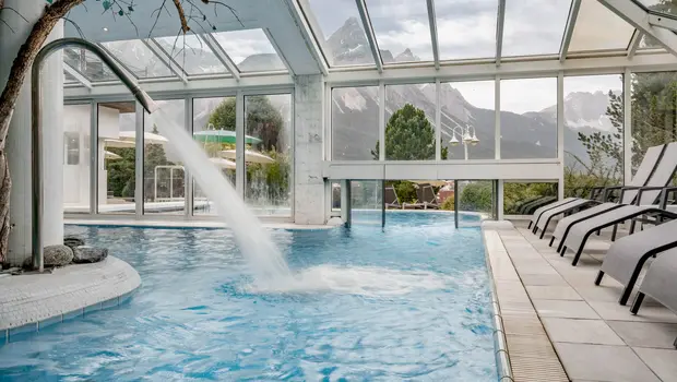 Innenpool mit Wasserfall und Panoramablick auf die Tiroler Berge
