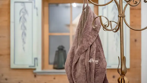 Flauschiger Alpenhof-Bademantel im gemütlichen Wellnessbereich mit Holz- und Kachel-Elementen